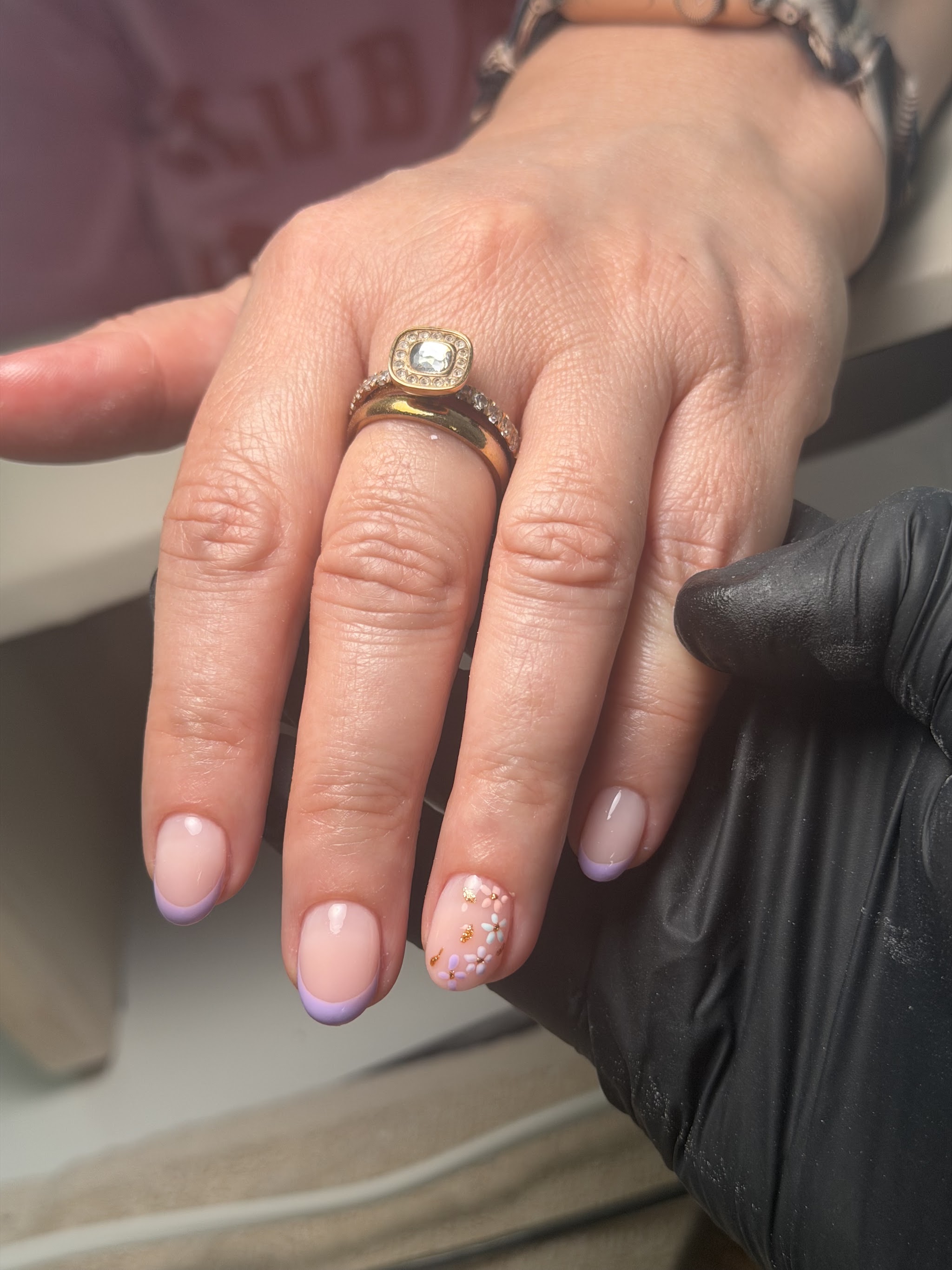 Hand met lila french tips en kleine bloemetjes op de ringvinger, vers gezet
