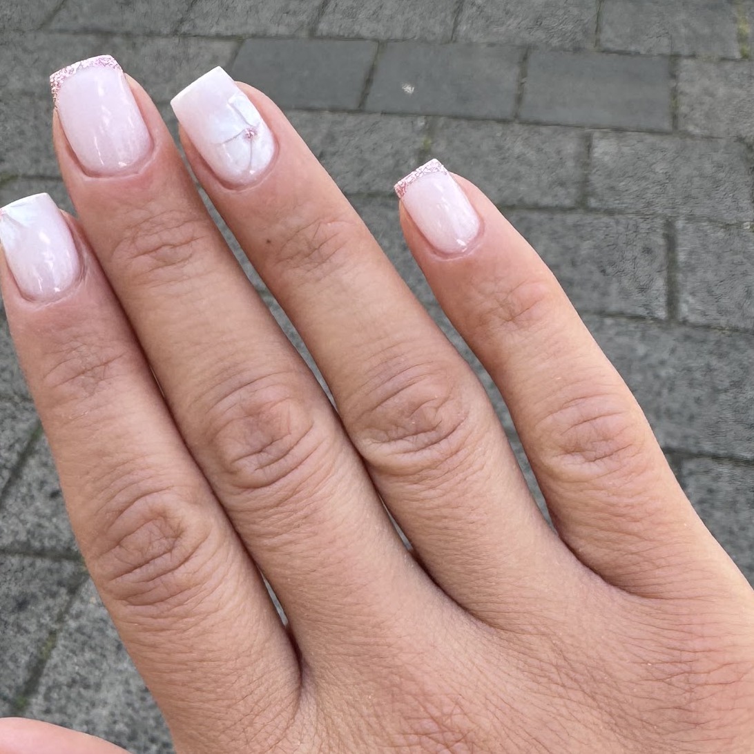 Korte nagels met een melkwitte basis en glitterrandjes